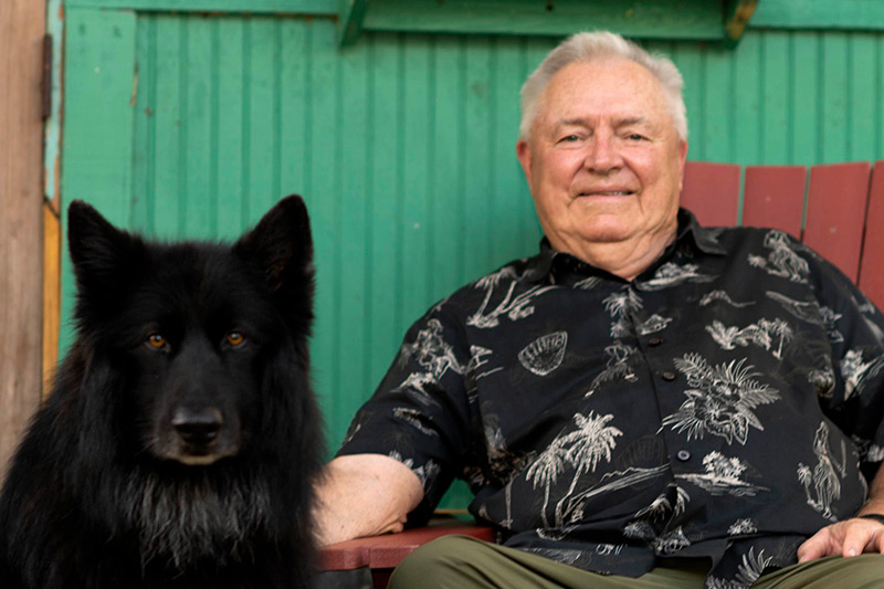 Man seated next to big black dog